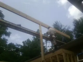 Carpenter setting a ridge beam over a new addition frame — Ice Dam Removal by Roofing Brothers in Hallandale