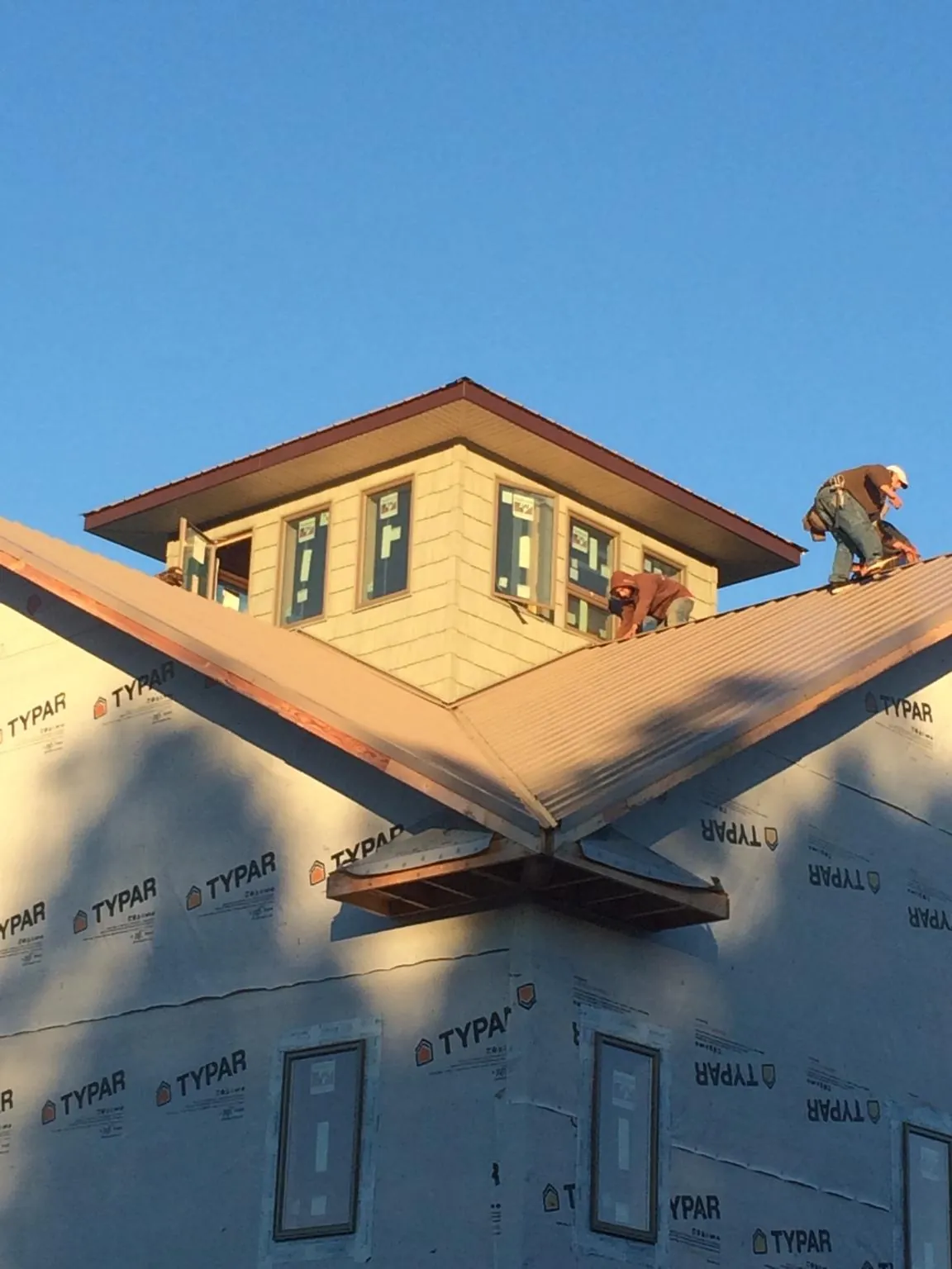 Roofers working around a rooftop cupola on a new metal roof at sunset — Roof Waterproofing in Hallandale by Roofing Brothers